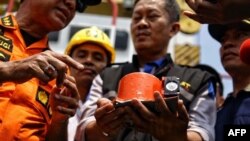 Para petugas tampak menunjukkan sebagian dari kotak hitam Lion Air no penerbangan JT610 yang bernasib naas, yaitu perekam data penerbangan (FDR), yang berhasil diangkat dari Laut Jawa, dalam operasi pencarian di perairan lepas pantai Karawang tanggal 1 November 2018 (foto: Pradita Utama/Detikcom/AFP)