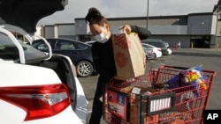 FILE - In this July 1, 2020 file photo, an Instacart worker loads groceries into her car in San Leandro, Calif. A California law that allows "gig workers" to be treated as independent contractors was ruled unconstitutional.