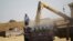 A Syrian man stands on a truck that's being filled with wheat in a field in Maarshamsha, Idlib countryside, May 31, 2015.