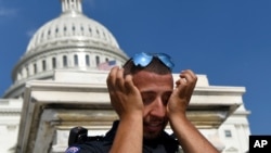 A Capitol Hill police officer wipes sweat from his eyes as he stands his post on the West side of Capitol Hill in Washington, D.C., July 20, 2019. The National Weather Service said "a dangerous heat wave" was expected to break record highs in some places.