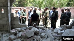 Army soldiers inspect the site of a suicide attack at a bus station in the government-held city of Hama in western Syria, in this handout picture provided by SANA on July 6, 2017, Syria.