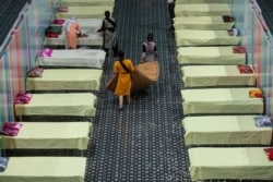 Workers arrange beds at a COVID-19 treatment facility newly set up at an indoor stadium in Gauhati, India, April 19, 2021.
