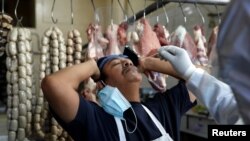 Personnel from Guatemala's health ministry perform a test on a vendor at a fresh produce market during the outbreak of the coronavirus disease (COVID-19), in Guatemala City, May 21, 2020. 