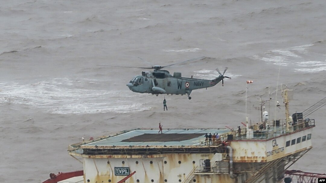 This handout photograph taken May 18, 2021 and released by Indian navy shows stranded workers from a barge being airlifted by naval personnel on an Indian navy helicopter during an evacuation operation, in the Arabian sea.