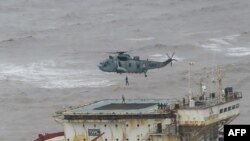This handout photograph taken May 18, 2021 and released by Indian navy shows stranded workers from a barge being airlifted by naval personnel on an Indian navy helicopter during an evacuation operation, in the Arabian sea.