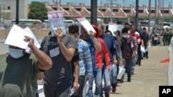 ARCHIVO - En esta fotografía de archivo del 25 de julio de 2019, agentes de la Patrulla Fronteriza de Estados Unidos devuelven a un grupo de migrantes al lado mexicano de la frontera mientras los funcionarios de inmigración mexicanos revisan la lista, en Nuevo Laredo, México.