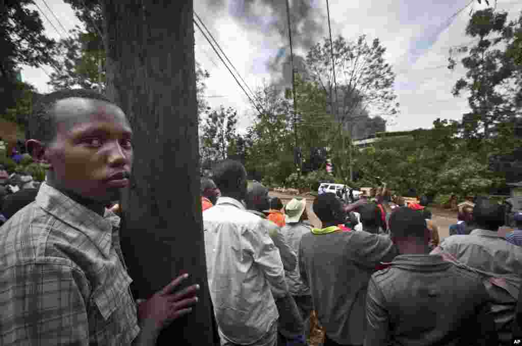 People look at a plume of black smoke billow over the Westgate Mall, following large explosions and heavy gunfire, in Nairobi, Sept. 23, 2013. 