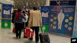 Calon penumpang melewati pos pemeriksaan kesehatan sebelum memasukin pemeriksaan imigrasi di Bandara International Beijing, China, 13 Januari 2020. 