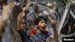 An Egyptian boy peers out of barbed wire during a protest in front of the Supreme Constitutional Court in Cairo, Egypt, Thursday June 14, 2012.