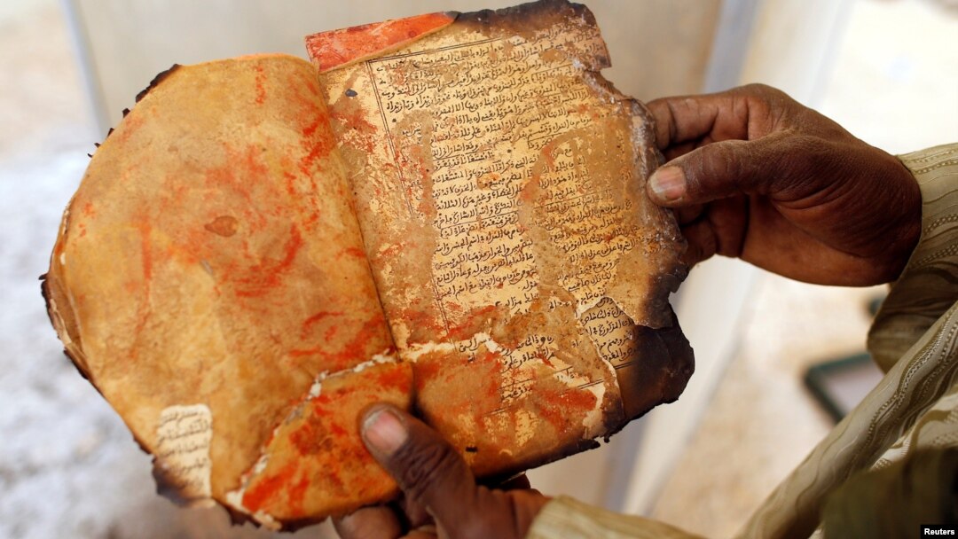 Seorang penjaga museum memperlihatkan manuskrip kuno yang terbakar di Ahmed Baba Institute, atau Ahmed Baba Centre for Documentation and Research, di Timbuktu, 31 Januari 2013 (foto: REUTERS/Benoit Tessier/Arsip)