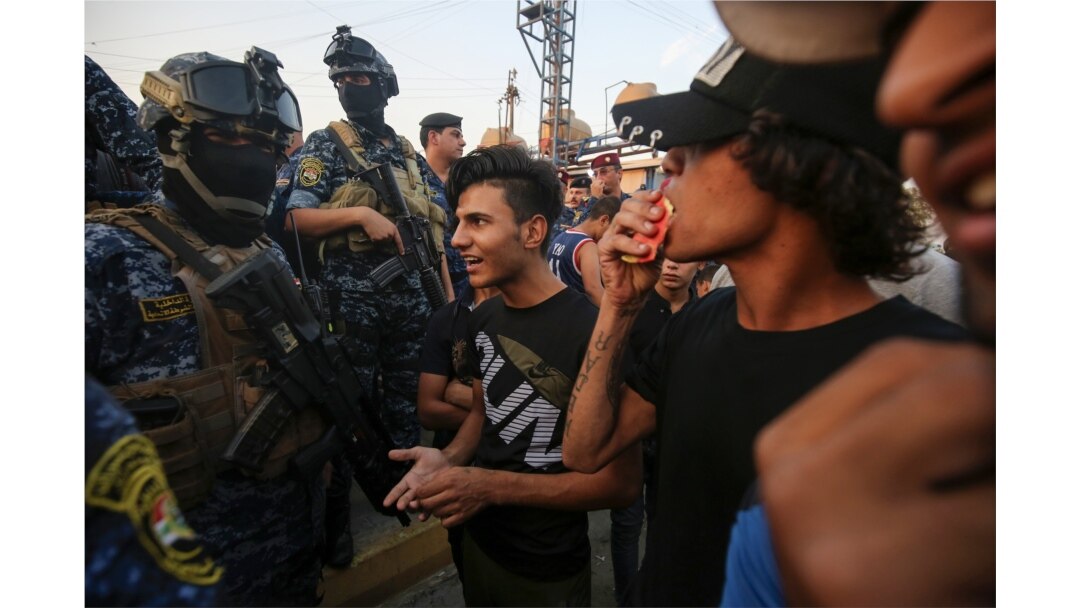 Iraqi protesters speaks with members of police in Baghdad's predominantly Shi'ite Sadr City, Oct. 7, 2019.