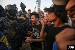 Iraqi protesters speaks with members of police in Baghdad's predominantly Shi'ite Sadr City, Oct. 7, 2019.