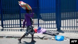 Un hombre pasa junto al cuerpo de una persona que recibió un disparo en Port-Au-Price, Haití, el 1 de abril de 2024. Foto de Clarens SIFFROY / AFP.