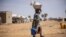 FILE - A woman walks at the Goudebo refugee camp for Malian refugees in Dori, Burkina Faso, Feb. 3, 2020. More than 8 000 Malian refugees live in in the Goudebo refugee camp.