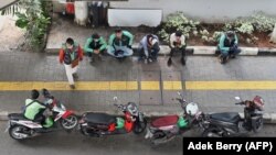 Pengemudi layanan ojek Gojek dan Grab enunggu penumpang di Jakarta pada 24 Juni 2020. (Foto: AFP/Adek Berry)