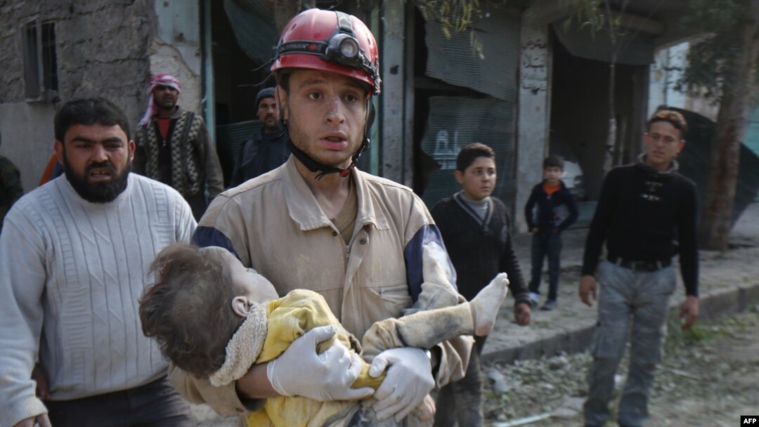 Seorang petugas pertahanan sipil menggendong mayat seorang anak yang terkena serangan udara di Aleppo, Suriah, Februari 2015. (AFP/AMC/Zein Al-Rifai)