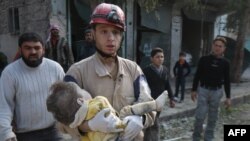 Seorang petugas pertahanan sipil menggendong mayat seorang anak yang terkena serangan udara di Aleppo, Suriah, Februari 2015. (AFP/AMC/Zein Al-Rifai)