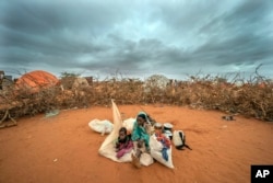 FILE - A Somali woman and child wait to be given a spot to settle at a camp for displaced people on the outskirts of Dollow, Somalia on Tuesday, Sept. 20, 2022. (AP Photo/Jerome Delay, File)