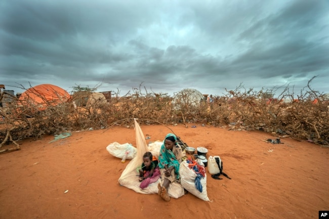 FILE - A Somali woman and child wait to be given a spot to settle at a camp for displaced people on the outskirts of Dollow, Somalia on Tuesday, Sept. 20, 2022. (AP Photo/Jerome Delay, File)