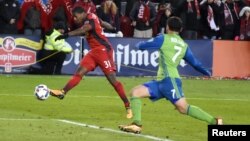 Armando Coope deToronto FC, à gauche, tire aux buts devant Cristian Roldan des Seattle Sounders lors d'un match de MLS, Canada, le 9 décembre 2017