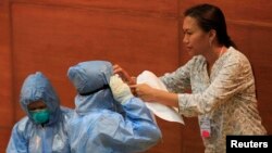 FILE - A Philippine health worker assists a colleague with protective suits and equipment during the "One Nation, One Direction for EBOLA Prevention" training at the Research Institute for Tropical Medicine hospital in Alabang, Muntinlupa, south of Manila. 