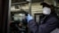 FILE - A New York subway rider wears protective gloves and a mask while holding onto a pole, March 19, 2020.
