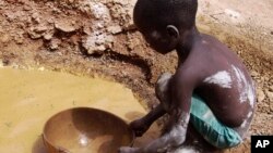 Abou Keita, âgée approximativement de cinq ans, tamise des pépites à la recherche de l’or dans la mine de Djikouloumba, près de la région de Kankan, Guinée, 27 avril 2008.