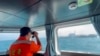 In this screen grab from video released by the Taiwan Coast Guard, a member of the Taiwan Coast Guard monitors a China Coast Guard boat as it passes near the coast of Matsu islands, Taiwan, Oct. 14, 2024. (Taiwan Coast Guard via AP)