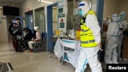 A security personnel in a protective suit keeps watch as medical workers attend to patients at the fever department of Tongji Hospital, a major facility for patients of COVID-19, in Wuhan, Hubei province, China Jan. 1, 2023.