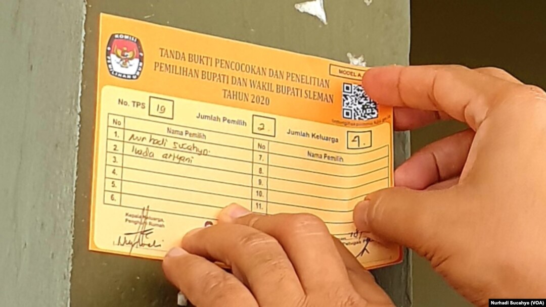 Seorang warga Sleman, DI Yogyakarta menempelkan stiker tanda akurasi data pemilih. Sleman menjadi salah satu kabupaten yang melaksanakan PIlkada 2020. (Foto: VOA/Nurhadi Sucahyo)