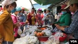 Garment factory workers wear face masks as they buy food on a lunch break near Propitious (Cambodia) Garment Ltd factory, in Kandal province, Cambodia, March 20, 2020. (Kann Vicheika/VOA Khmer) 