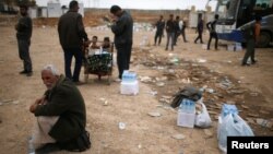 Displaced Iraqis wait to get food supplies as Iraqi forces battle with Islamic State militants, in western Mosul, Iraq, March 28, 2017. 