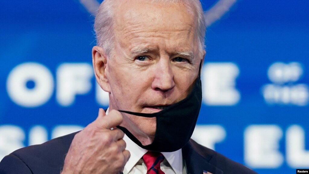 U.S. President-elect Joe Biden adjusts his face mask as he speaks about his plan to administer coronavirus disease vaccines to the U.S. population, during a news conference at Biden