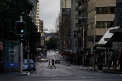 Pedestrians cross an unusually quiet street in the city center during a lockdown to curb the spread of the coronavirus outbreak in Sydney, Australia, June 29, 2021.