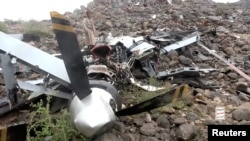 A man stands near the wreckage of a U.S. MQ-9 drone that Houthis claim they shot out of the sky, in a location given as Saada Governorate, Yemen, in this undated still image taken from a video obtained on Aug. 4, 2024. (Houthi Military Media via Reuters)