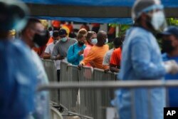 پاناما سٹی میں رضاکار ویکسین کی ٹیسٹنگ کے لیے قطار میں کھڑے اپنی باری کا انتظار کر رہے ہیں۔ 15 جنوری 2021