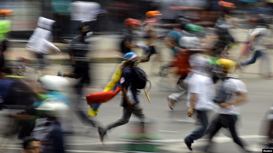 Demonstrators run during clashes with riot security forces at a protest against Venezuelan President Nicolas Maduro's government, in Caracas, Venezuela, May 30, 2017. 