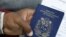 FILE -- A Venezuelan migrant holds his passport at a queue to get a temporary residency permit outside the immigration office in Lima, Peru, Aug. 20, 2018. 