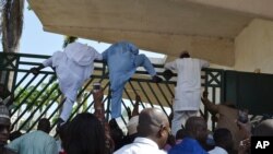 Unidentified lawmakers scale the parliament gate, in Abuja, Nigeria. Nov. 20, 2014.