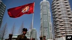 FILE - North Korean soldiers carry the Korean People's Army flag as they walk past residential buildings along Ryomyong street, in Pyongyang, North Korea, April 13, 2017.