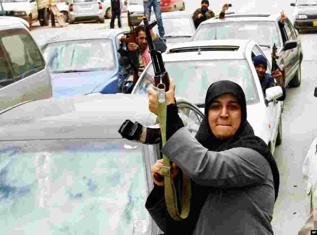 A rebel fighter supporter shoots an AK-47 rifle as she reacts to the news of the withdrawal of Libyan leader Muammar Gadhafi's forces from Benghazi, March 20, 2011. (Reuters/Goran Tomasevic)