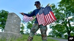 Trung sĩ Hải quân đã nghỉ hưu Bob Workman ở Boston và là cựu chỉ huy của Cảnh sát Boston VFW thay cờ tại mộ của các cựu chiến binh trước Lễ Chiến sĩ Trận vong ngày 27/5/2021, tại Nghĩa trang Fairview ở Boston.