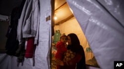 Syrian refugee Ayesha al-Abed, 21, holds and kisses her daughter Rayan, 18 months old, before she breaks her fast on the first day of Ramadan, at an informal refugee camp in Bhannine, Lebanon, April 13, 2021.