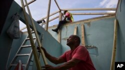 Pedro Deschamps helps workers hired by FEMA to carry out the installation of a temporary awning roof at his house, which suffered damage during Hurricane Maria, in San Juan, Puerto Rico, Nov. 15, 2017. 