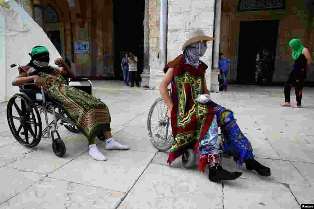 Masked Palestinians rest in wheelchairs before clashes with Israeli police erupted during the holy month of Ramadan on the compound known to Muslims as Noble Sanctuary and to Jews as Temple Mount in Jerusalem&#39;s Old City.