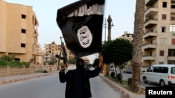 FILE - A member loyal to the Islamic State waves an IS flag in Raqqa, June 29, 2014.