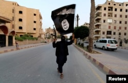 A member of the Islamic State carries the militant group's signature black flag in Raqqa, Syria in 2014.
