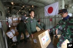 Personel militer Indonesia dan Jepang membongkar bantuan dari sebuah pesawat kargo Angkatan Udara Jepang di bandara Mutiara Sis Al-Jufri di Palu, Sulawesi Tengah, Indonesia, Sabtu, 6 Oktober 2018.