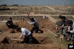 FILE - Relatives and friends dig the graves of civilians killed during fighting between Iraqi security forces and Islamic State militants on the western side of Mosul, Iraq, March 25, 2017.