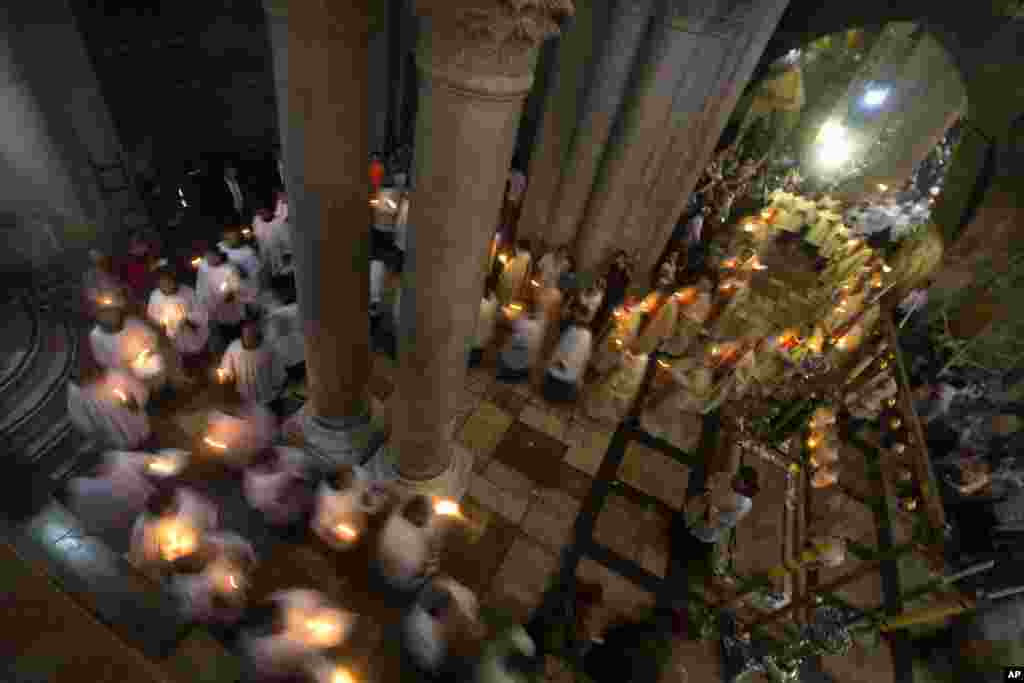 Para rohaniwan menyalakan lilin dalam prosesi Paskah di Gereja Holy Sepulchre, yang diyakini oleh banyak orang merupakan lokasi penyaliban dan penguburan Yesus Kristus, di Kota Tua Yerusalem.